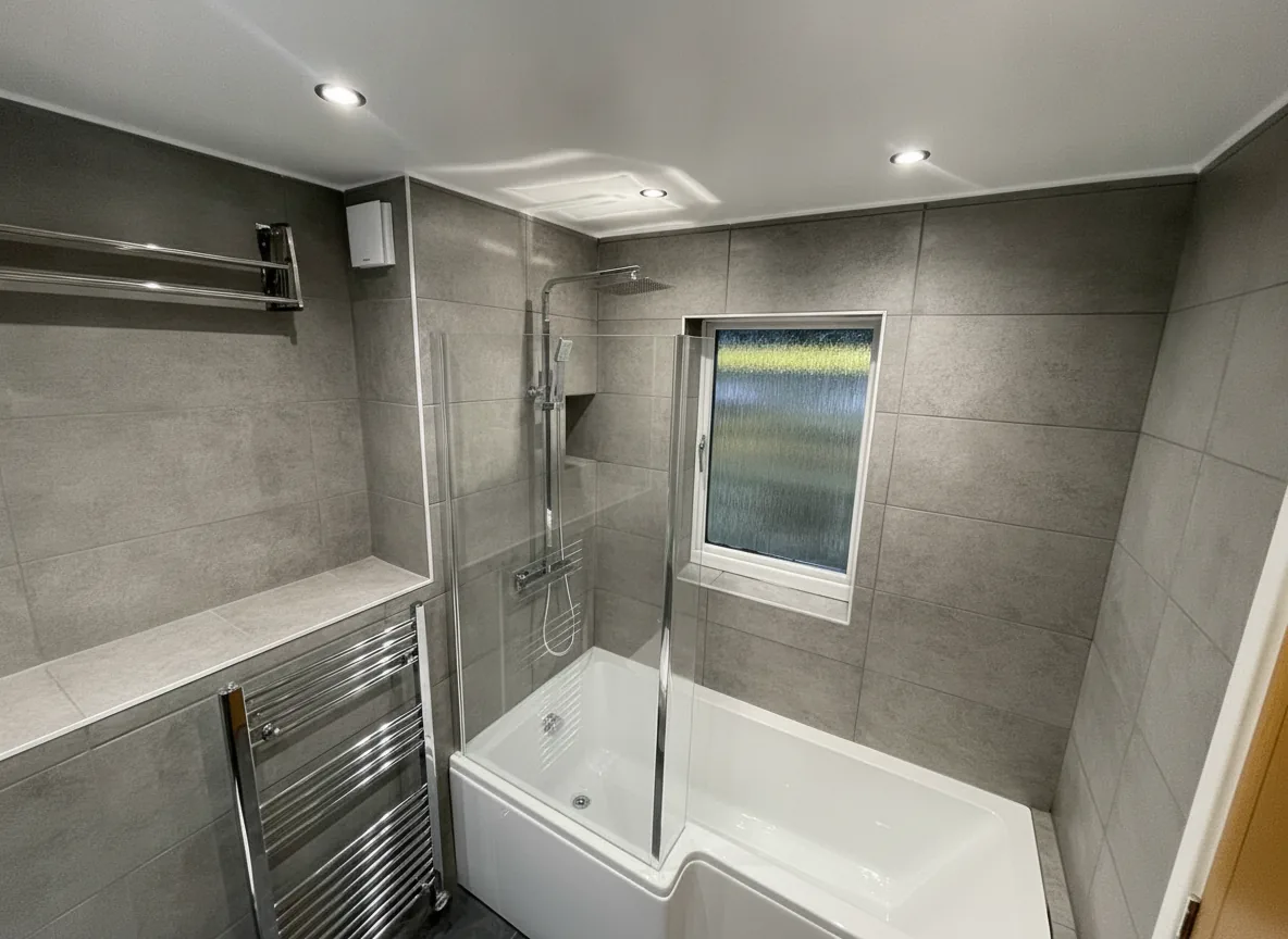 Grey-tiled bathroom with L-shaped shower bath, chrome towel radiator and rainfall shower, Barnet